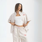 Unisex button-up shirt with a boxy fit and midi crop, featuring sailor stripes in sand beige and white. Embroidered "Humble State of Mind" logo in burgundy red on the back and "Originals" embroidery on the front. Made from 100% thick cotton for a relaxed, summery style.