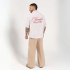 Unisex button-up shirt with a boxy fit and midi crop, featuring sailor stripes in sand beige and white. Embroidered "Humble State of Mind" logo in burgundy red on the back and "Originals" embroidery on the front. Made from 100% thick cotton for a relaxed, summery style.