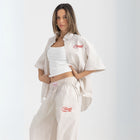 Unisex button-up shirt with a boxy fit and midi crop, featuring sailor stripes in sand beige and white. Embroidered "Humble State of Mind" logo in burgundy red on the back and "Originals" embroidery on the front. Made from 100% thick cotton for a relaxed, summery style.