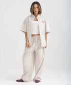 Unisex button-up shirt with a boxy fit and midi crop, featuring sailor stripes in sand beige and white. Embroidered "Humble State of Mind" logo in burgundy red on the back and "Originals" embroidery on the front. Made from 100% thick cotton for a relaxed, summery style.