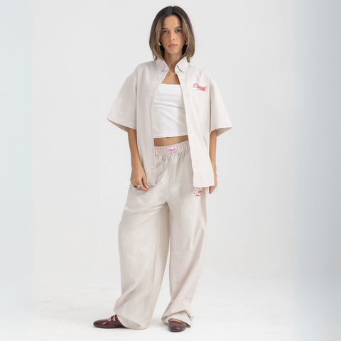 Unisex button-up shirt with a boxy fit and midi crop, featuring sailor stripes in sand beige and white. Embroidered "Humble State of Mind" logo in burgundy red on the back and "Originals" embroidery on the front. Made from 100% thick cotton for a relaxed, summery style.
