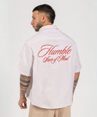 Unisex button-up shirt with a boxy fit and midi crop, featuring sailor stripes in sand beige and white. Embroidered "Humble State of Mind" logo in burgundy red on the back and "Originals" embroidery on the front. Made from 100% thick cotton for a relaxed, summery style.