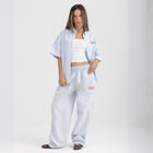 Unisex button-up shirt with a boxy fit and midi crop, featuring sailor stripes in ocean blue and white. Embroidered "Humble State of Mind" logo in burgundy red on the back and "Originals" embroidery on the front. Made from 100% thick cotton for a relaxed, summery style.