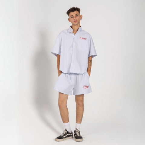 Unisex button-up shirt with a boxy fit and midi crop, featuring sailor stripes in ocean blue and white. Embroidered "Humble State of Mind" logo in burgundy red on the back and "Originals" embroidery on the front. Made from 100% thick cotton for a relaxed, summery style.