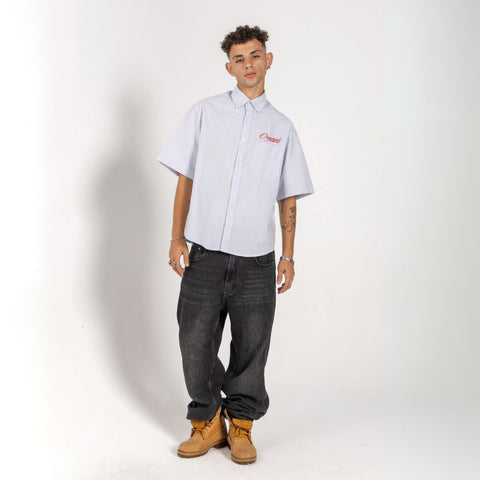 Unisex button-up shirt with a boxy fit and midi crop, featuring sailor stripes in ocean blue and white. Embroidered "Humble State of Mind" logo in burgundy red on the back and "Originals" embroidery on the front. Made from 100% thick cotton for a relaxed, summery style.