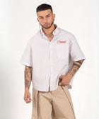Unisex button-up shirt with a boxy fit and midi crop, featuring sailor stripes in sand beige and white. Embroidered "Humble State of Mind" logo in burgundy red on the back and "Originals" embroidery on the front. Made from 100% thick cotton for a relaxed, summery style.