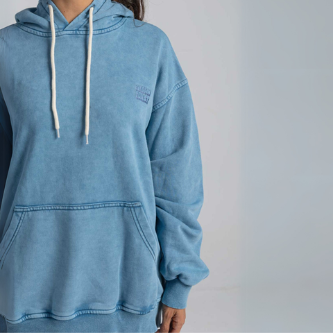 Model wearing the BROWNTOAST ASSID Hoodie in denim blue — unisex cotton-blend hoodie with relaxed fit and unique dye variations acid washed/stone washed. Each piece from the ASSID drop is one of a kind, made in Egypt through a special process for an elevated everyday look.