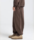 Model wearing the BROWNTOAST Core Barrel Sweats from the Core Drop — unisex cotton sweatpants in coffee brown with a relaxed barrel-shaped leg, elastic waistband, and side pockets. Made in Egypt for structured comfort and clean everyday style.