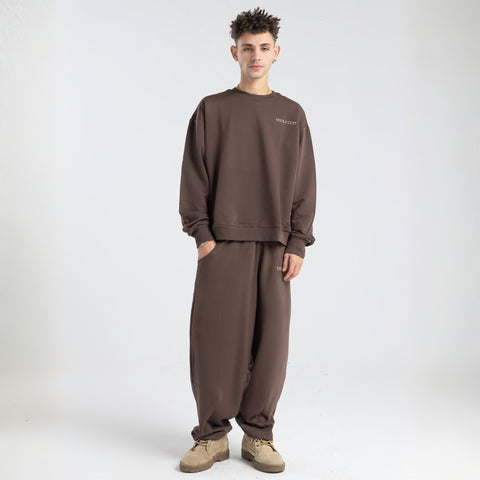 Model wearing the BROWNTOAST Core Barrel Sweats from the Core Drop — unisex cotton sweatpants in coffee brown with a relaxed barrel-shaped leg, elastic waistband, and side pockets. Made in Egypt for structured comfort and clean everyday style.