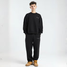 Model wearing the BROWNTOAST Core Barrel Sweats from the Core Drop — unisex cotton sweatpants in black with a relaxed barrel-shaped leg, elastic waistband, and side pockets. Made in Egypt for structured comfort and clean everyday style.