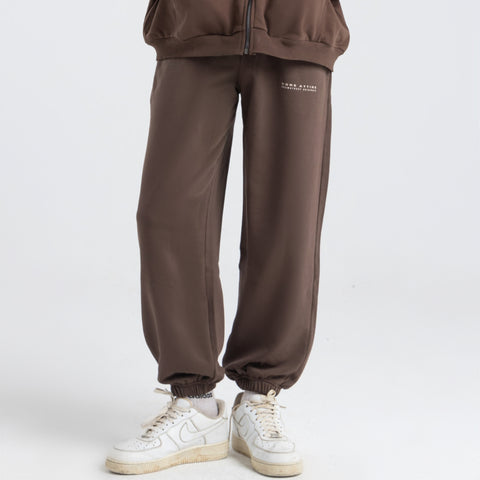 Model wearing the BROWNTOAST Core Cuffed Sweats from the Core Drop in coffee brown — unisex cotton sweatpants with cuffed ankles, adjustable drawstring waist, and side pockets. Made in Egypt for a relaxed, structured, and effortless everyday fit.