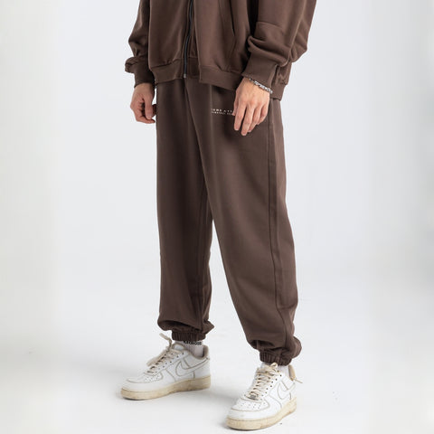 Model wearing the BROWNTOAST Core Cuffed Sweats from the Core Drop in coffee brown — unisex cotton sweatpants with cuffed ankles, adjustable drawstring waist, and side pockets. Made in Egypt for a relaxed, structured, and effortless everyday fit.