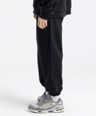 Model wearing the BROWNTOAST Core Cuffed Sweats from the Core Drop in black — unisex cotton sweatpants with cuffed ankles, adjustable drawstring waist, and side pockets. Made in Egypt for a relaxed, structured, and effortless everyday fit.