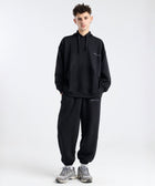Model wearing the BROWNTOAST Core Cuffed Sweats from the Core Drop in black — unisex cotton sweatpants with cuffed ankles, adjustable drawstring waist, and side pockets. Made in Egypt for a relaxed, structured, and effortless everyday fit.