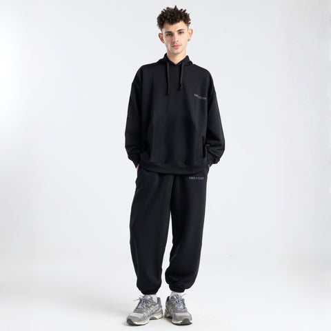 Model wearing the BROWNTOAST Core Cuffed Sweats from the Core Drop in black — unisex cotton sweatpants with cuffed ankles, adjustable drawstring waist, and side pockets. Made in Egypt for a relaxed, structured, and effortless everyday fit.