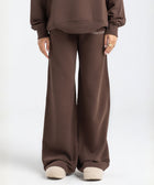 Model wearing the BROWNTOAST Core Flared Sweats from the Core Drop — women’s cotton-lycra flared sweatpants with a mid-rise waist, adjustable drawstring, and subtle seam detailing. Made in Egypt for a soft, flattering, and effortless everyday look. In coffee brown color.