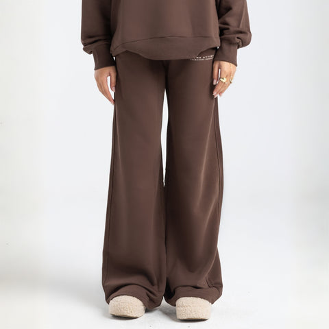 Model wearing the BROWNTOAST Core Flared Sweats from the Core Drop — women’s cotton-lycra flared sweatpants with a mid-rise waist, adjustable drawstring, and subtle seam detailing. Made in Egypt for a soft, flattering, and effortless everyday look. In coffee brown color.