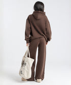 Model wearing the BROWNTOAST Core Flared Sweats from the Core Drop — women’s cotton-lycra flared sweatpants with a mid-rise waist, adjustable drawstring, and subtle seam detailing. Made in Egypt for a soft, flattering, and effortless everyday look. In coffee brown color.