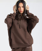 Model wearing the BROWNTOAST Core Hoodie from the Core Drop in coffee brown — a relaxed unisex hoodie with an adjustable drawstring hood, kangaroo pocket, and front silk-screen print. Made in Egypt from a soft cotton blend for an elevated everyday look.