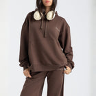 Model wearing the BROWNTOAST Core Hoodie from the Core Drop in coffee brown — a relaxed unisex hoodie with an adjustable drawstring hood, kangaroo pocket, and front silk-screen print. Made in Egypt from a soft cotton blend for an elevated everyday look.