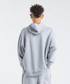 Model wearing the BROWNTOAST Core Hoodie from the Core Drop in light grey— a relaxed unisex hoodie with an adjustable drawstring hood, kangaroo pocket, and front silk-screen print. Made in Egypt from a soft cotton blend for an elevated everyday look.