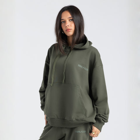 Model wearing the BROWNTOAST Core Hoodie from the Core Drop in olive green— a relaxed unisex hoodie with an adjustable drawstring hood, kangaroo pocket, and front silk-screen print. Made in Egypt from a soft cotton blend for an elevated everyday look.