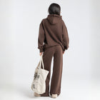 Model wearing the BROWNTOAST Core Hoodie from the Core Drop in coffee brown — a relaxed unisex hoodie with an adjustable drawstring hood, kangaroo pocket, and front silk-screen print. Made in Egypt from a soft cotton blend for an elevated everyday look.