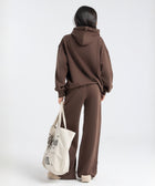 Model wearing the BROWNTOAST Core Hoodie from the Core Drop in coffee brown — a relaxed unisex hoodie with an adjustable drawstring hood, kangaroo pocket, and front silk-screen print. Made in Egypt from a soft cotton blend for an elevated everyday look.