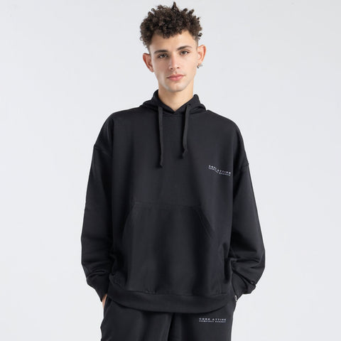 Model wearing the BROWNTOAST Core Hoodie from the Core Drop in black— a relaxed unisex hoodie with an adjustable drawstring hood, kangaroo pocket, and front silk-screen print. Made in Egypt from a soft cotton blend for an elevated everyday look.