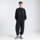 Model wearing the BROWNTOAST Core Hoodie from the Core Drop in black— a relaxed unisex hoodie with an adjustable drawstring hood, kangaroo pocket, and front silk-screen print. Made in Egypt from a soft cotton blend for an elevated everyday look.