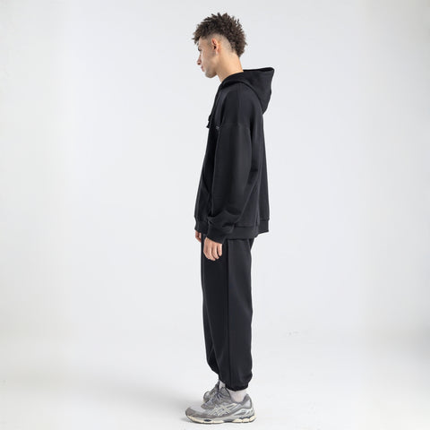  Model wearing the BROWNTOAST Core Hoodie from the Core Drop in black— a relaxed unisex hoodie with an adjustable drawstring hood, kangaroo pocket, and front silk-screen print. Made in Egypt from a soft cotton blend for an elevated everyday look.