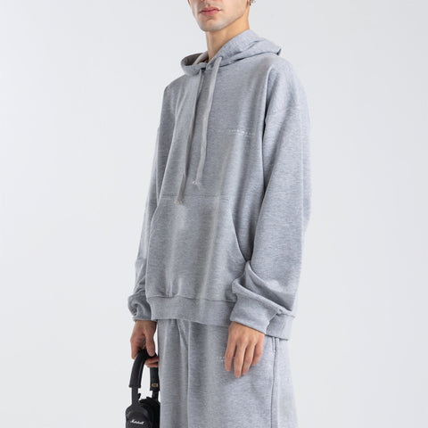 Model wearing the BROWNTOAST Core Hoodie from the Core Drop in light grey— a relaxed unisex hoodie with an adjustable drawstring hood, kangaroo pocket, and front silk-screen print. Made in Egypt from a soft cotton blend for an elevated everyday look.