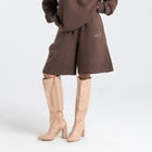 Model wearing the BROWNTOAST Core Long Shorts from the Core Drop in coffee brown — relaxed unisex cotton-lycra shorts with front piping detail, side pockets, and an adjustable drawstring waist. Knee-length design balancing bermuda and short fit, made in Egypt for everyday comfort and style.