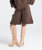 Model wearing the BROWNTOAST Core Long Shorts from the Core Drop in coffee brown — relaxed unisex cotton-lycra shorts with front piping detail, side pockets, and an adjustable drawstring waist. Knee-length design balancing bermuda and short fit, made in Egypt for everyday comfort and style.