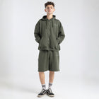 Model wearing the BROWNTOAST Core Long Shorts from the Core Drop in olive green — relaxed unisex cotton-lycra shorts with front piping detail, side pockets, and an adjustable drawstring waist. Knee-length design balancing bermuda and short fit, made in Egypt for everyday comfort and style.