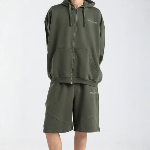 Model wearing the BROWNTOAST Core Long Shorts from the Core Drop in olive green — relaxed unisex cotton-lycra shorts with front piping detail, side pockets, and an adjustable drawstring waist. Knee-length design balancing bermuda and short fit, made in Egypt for everyday comfort and style.