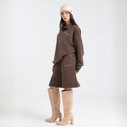 Model wearing the BROWNTOAST Core Long Shorts from the Core Drop in coffee brown — relaxed unisex cotton-lycra shorts with front piping detail, side pockets, and an adjustable drawstring waist. Knee-length design balancing bermuda and short fit, made in Egypt for everyday comfort and style.