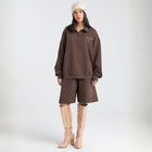 Model wearing the BROWNTOAST Core Long Shorts from the Core Drop in coffee brown — relaxed unisex cotton-lycra shorts with front piping detail, side pockets, and an adjustable drawstring waist. Knee-length design balancing bermuda and short fit, made in Egypt for everyday comfort and style.