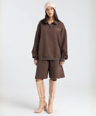 Model wearing the BROWNTOAST Core Long Shorts from the Core Drop in coffee brown — relaxed unisex cotton-lycra shorts with front piping detail, side pockets, and an adjustable drawstring waist. Knee-length design balancing bermuda and short fit, made in Egypt for everyday comfort and style.