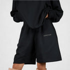 Model wearing the BROWNTOAST Core Long Shorts from the Core Drop in black — relaxed unisex cotton-lycra shorts with front piping detail, side pockets, and an adjustable drawstring waist. Knee-length design balancing bermuda and short fit, made in Egypt for everyday comfort and style.