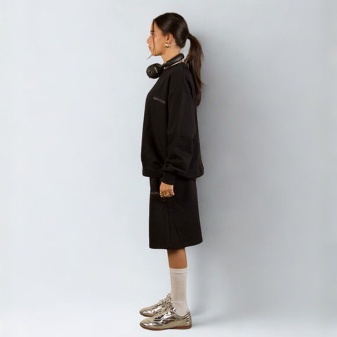 Model wearing the BROWNTOAST Core Long Shorts from the Core Drop in black — relaxed unisex cotton-lycra shorts with front piping detail, side pockets, and an adjustable drawstring waist. Knee-length design balancing bermuda and short fit, made in Egypt for everyday comfort and style.