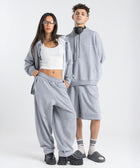 Model wearing the BROWNTOAST Core Long Shorts from the Core Drop in light grey — relaxed unisex cotton-lycra shorts with front piping detail, side pockets, and an adjustable drawstring waist. Knee-length design balancing bermuda and short fit, made in Egypt for everyday comfort and style.