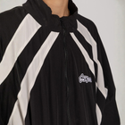 Model wearing the BROWNTOAST Compton Tracksuit Jacket — unisex oversized polyester track jacket with a dual-function zipper and BTO rubber and embroidered logos. Inspired by old-school Compton style and 80s hip-hop culture. Available in black and white.