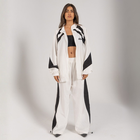 Model wearing the BROWNTOAST Compton Tracksuit Jacket — unisex oversized polyester track jacket with a dual-function zipper and BTO rubber and embroidered logos. Inspired by old-school Compton style and 80s hip-hop culture. Available in black and white.