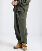 Model wearing the BROWNTOAST Core Barrel Sweats from the Core Drop — unisex cotton sweatpants in light grey with a relaxed barrel-shaped leg, elastic waistband, and side pockets. Made in Egypt for structured comfort and clean everyday style.