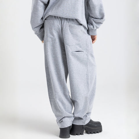 Model wearing the BROWNTOAST Core Barrel Sweats from the Core Drop — unisex cotton sweatpants in light grey with a relaxed barrel-shaped leg, elastic waistband, and side pockets. Made in Egypt for structured comfort and clean everyday style.