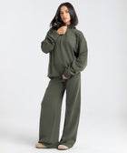 Model wearing the BROWNTOAST Core Flared Sweats from the Core Drop — women’s cotton-lycra flared sweatpants with a mid-rise waist, adjustable drawstring, and subtle seam detailing. Made in Egypt for a soft, flattering, and effortless everyday look. In olive green color.