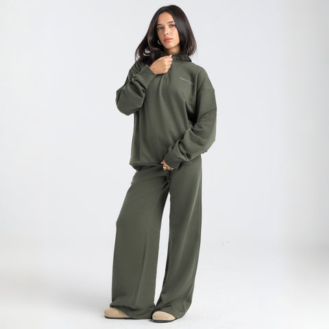 Model wearing the BROWNTOAST Core Flared Sweats from the Core Drop — women’s cotton-lycra flared sweatpants with a mid-rise waist, adjustable drawstring, and subtle seam detailing. Made in Egypt for a soft, flattering, and effortless everyday look. In olive green color.