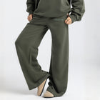 Model wearing the BROWNTOAST Core Flared Sweats from the Core Drop — women’s cotton-lycra flared sweatpants with a mid-rise waist, adjustable drawstring, and subtle seam detailing. Made in Egypt for a soft, flattering, and effortless everyday look. In olive green color.