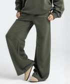 Model wearing the BROWNTOAST Core Flared Sweats from the Core Drop — women’s cotton-lycra flared sweatpants with a mid-rise waist, adjustable drawstring, and subtle seam detailing. Made in Egypt for a soft, flattering, and effortless everyday look. In olive green color.